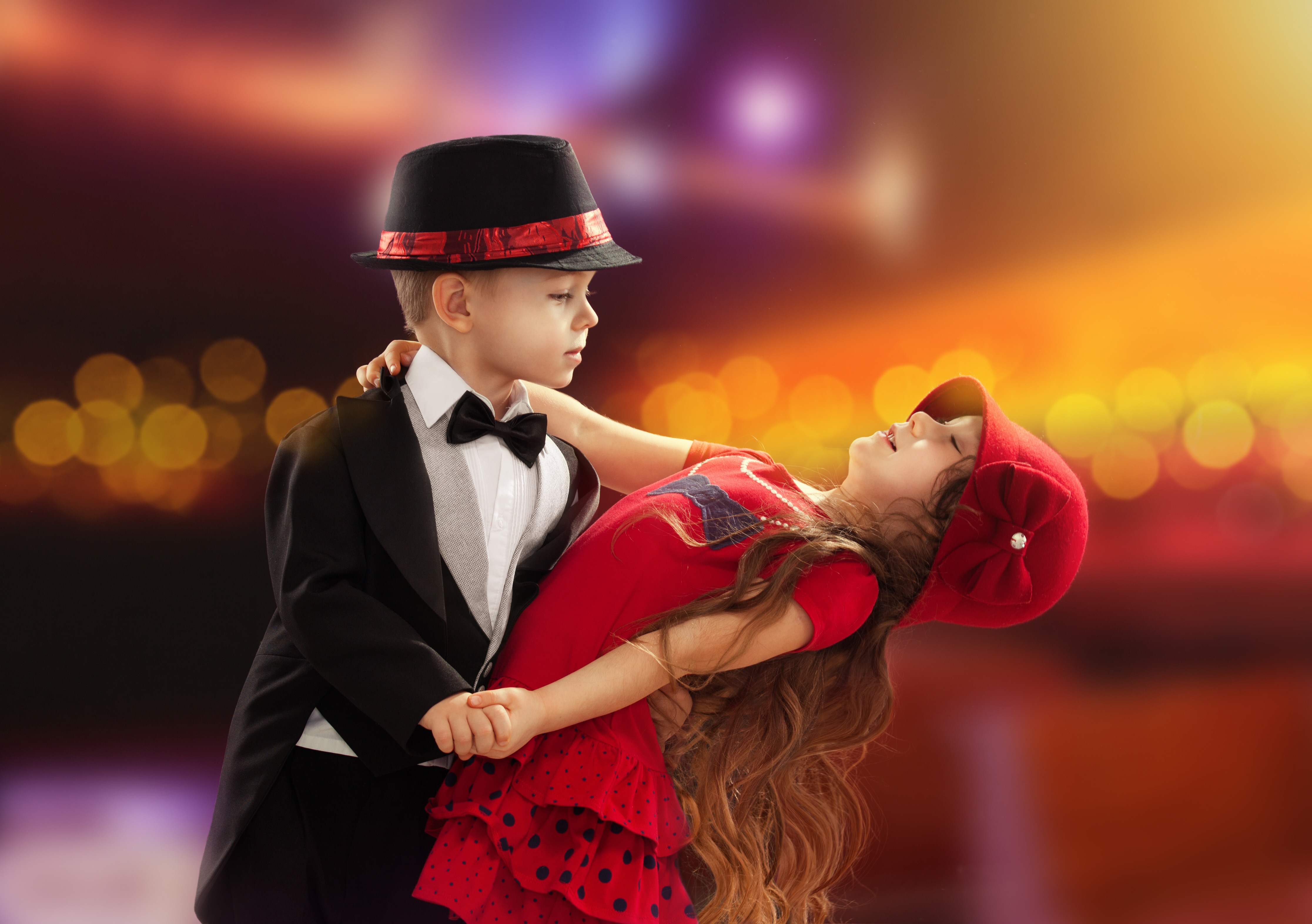 a young boy and girl ballroom dancing in fancy clothing